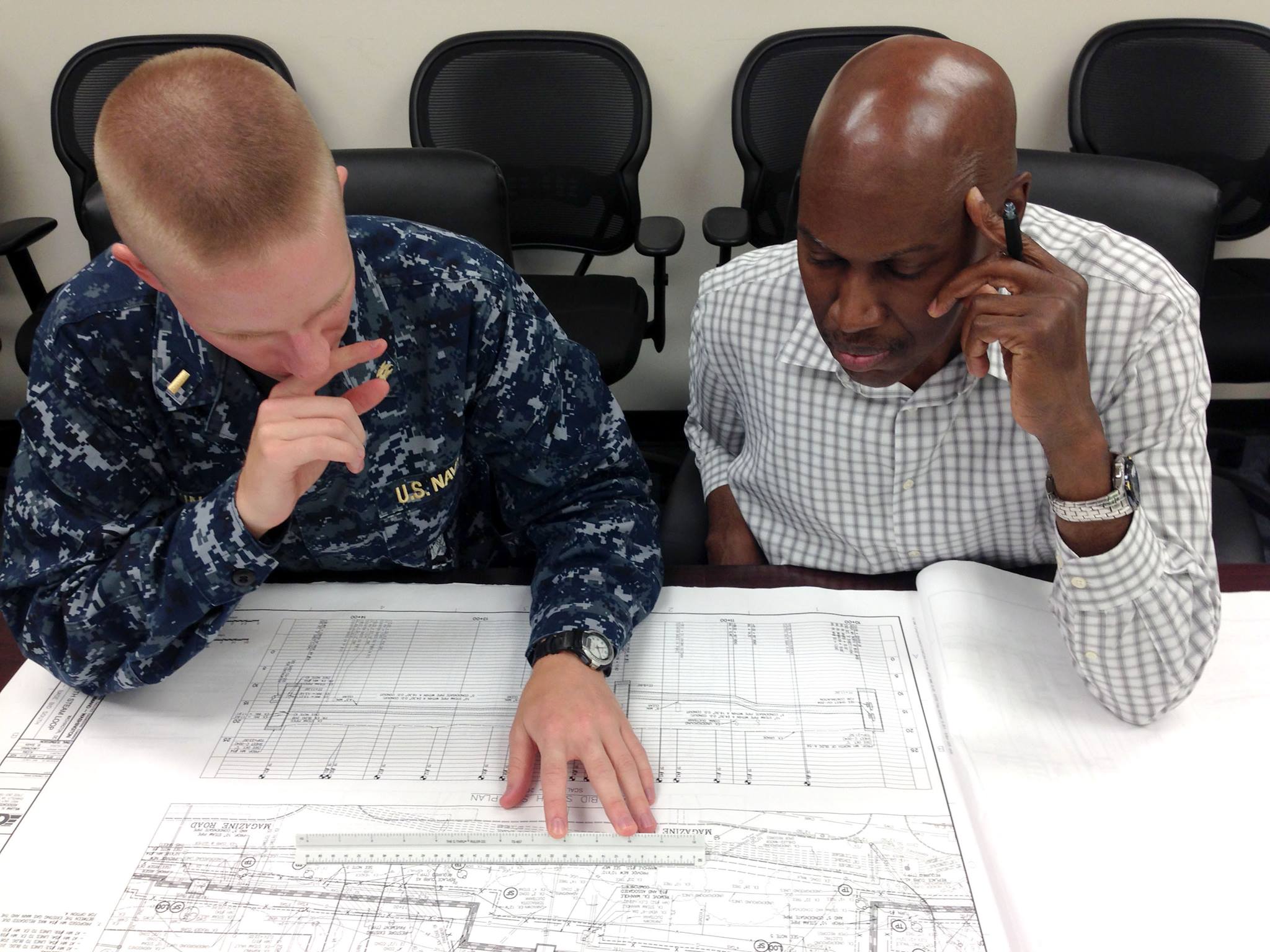NAVFAC engineering personnel reviewing underground utility drawings at a table