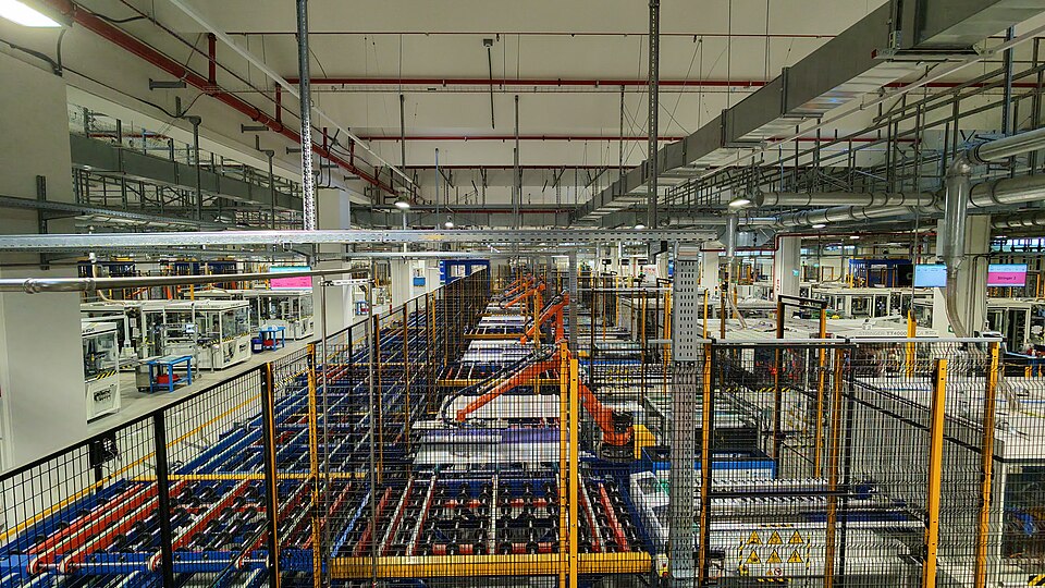 An automated factory production line with industrial robotic arms, enclosed machinery and safety barriers.